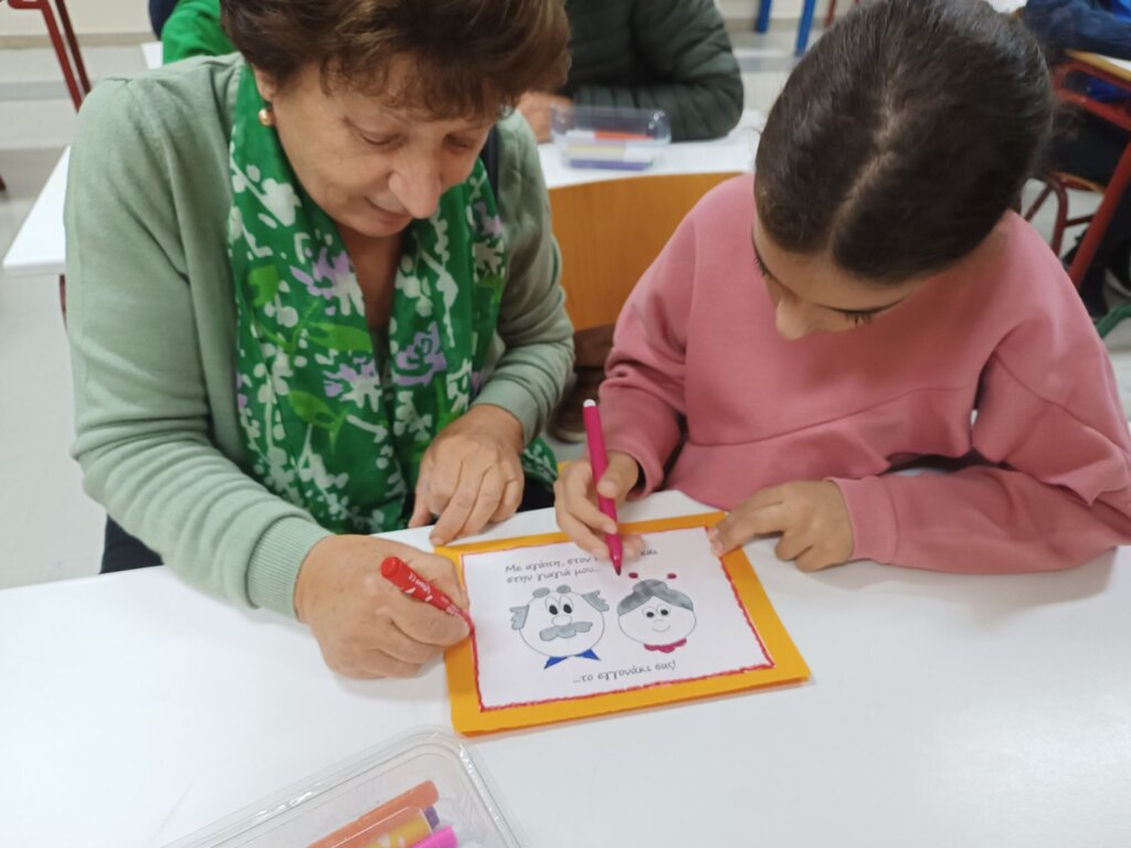 Παιδιά και παππούδες σε εκδήλωση του ΚΔΑΠ «Φρούριο» Τρικάλων, δημιουργώντας κάρτες και χορεύοντας μαζί σε γιορτή αγάπης.