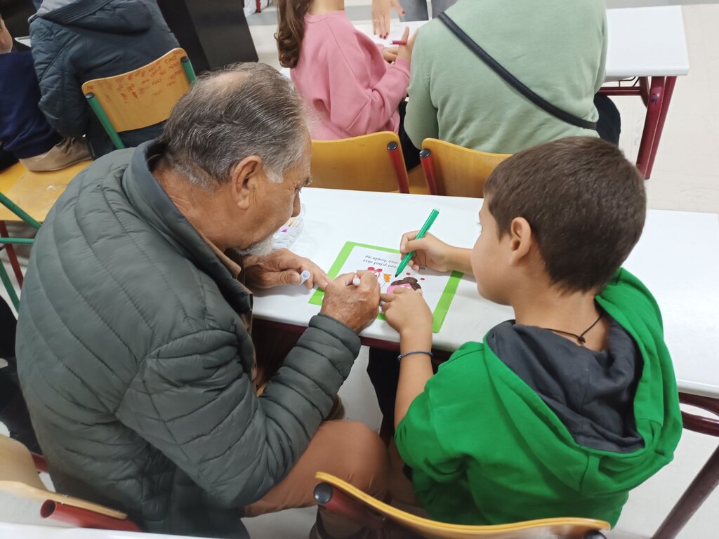 Παιδιά και παππούδες σε εκδήλωση του ΚΔΑΠ «Φρούριο» Τρικάλων, δημιουργώντας κάρτες και χορεύοντας μαζί σε γιορτή αγάπης.